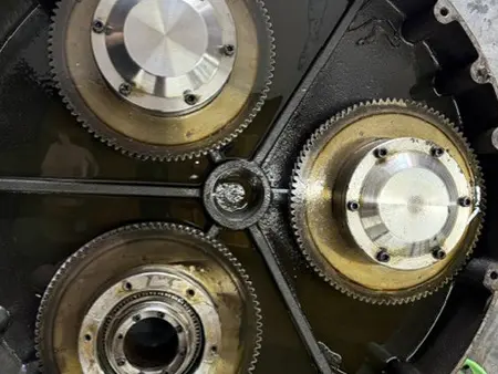 Concrete grinder gearbox opened for inspection before repair, showing planetary gears and drive components.