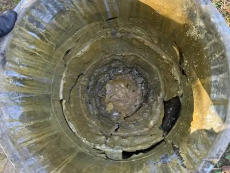 Mixing bucket with hardened concrete joint filler residue before cleaning and preparation for repair work.